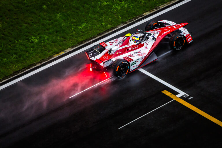 Aerial rear shot of Oliver Rowland on-track in the #1 car with spray coming from the rear of the car.